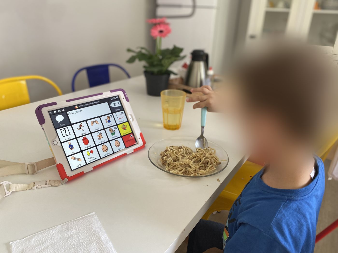 Criança usando o sistema de comunicação no tablet durante a refeição